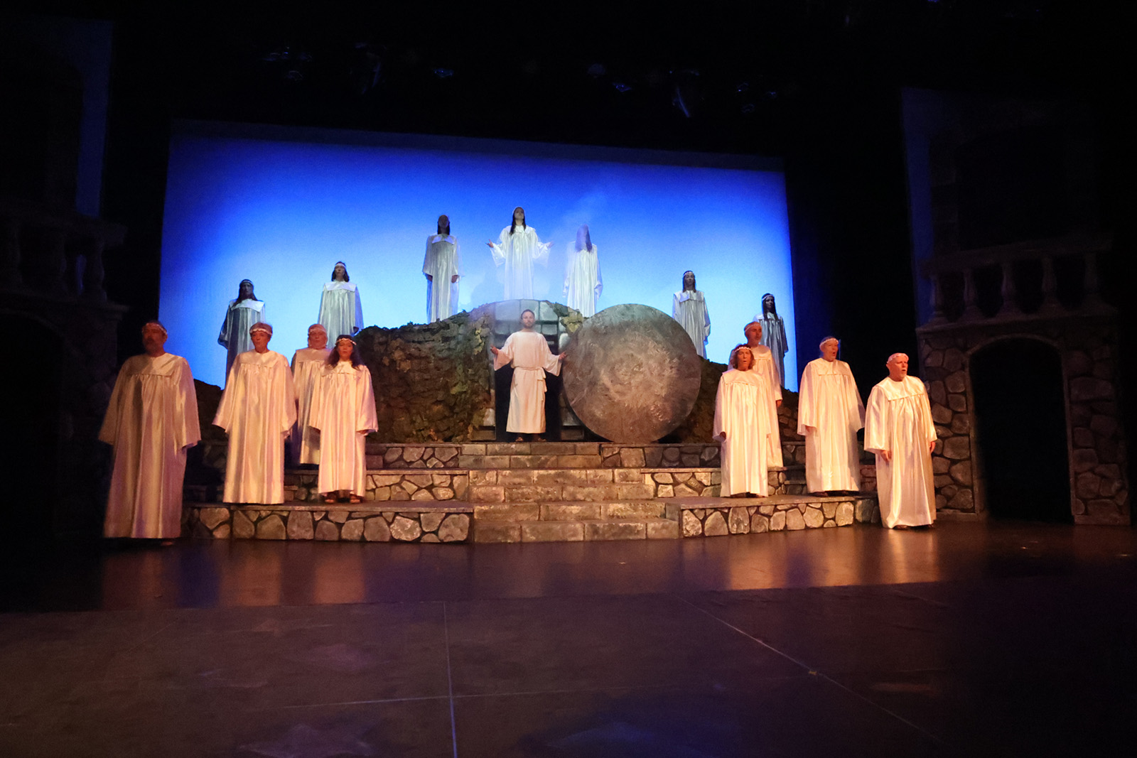 Jesus stands in front of a tomb, surrounded by angels.